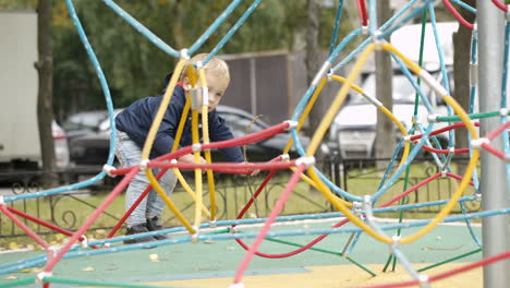 happy little boy climbing on playground equipment