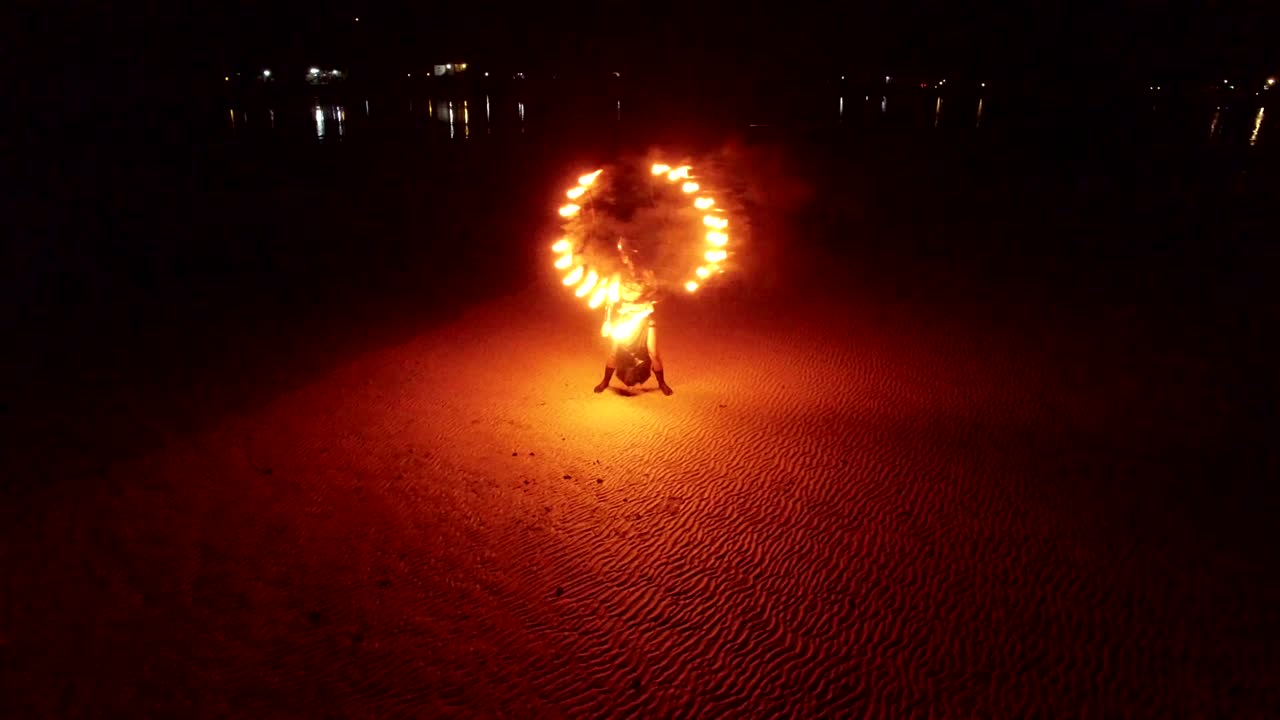 espectáculo de fuego de baile en la playa de bancos de arena al atardecer