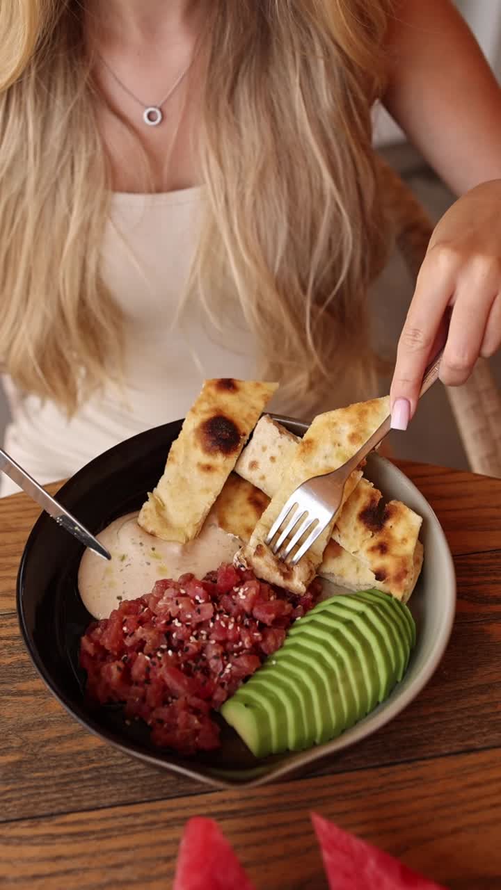 mujer comiendo una deliciosa comida con pan plano, sashimi de atún y aguacate