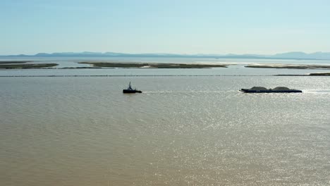 aerial of ship towing sand in murky waters within the coast