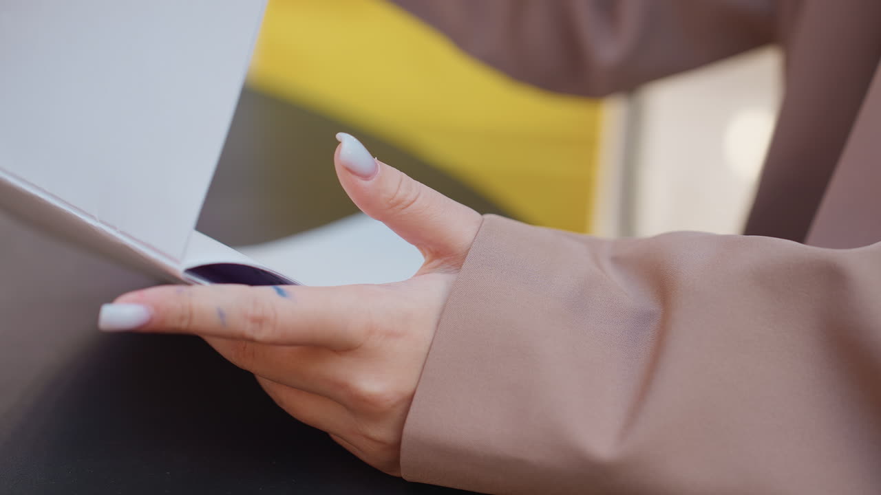 esamina la brochure e il dispositivo mobile, primo piano di una donna che analizza la brochure e lo smartphone, scatto mirato di una donna che valuta la brochure promozionale e il cellulare all'interno di un centro commerciale