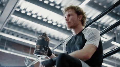 attractive fighter drinking water in fitness center. sportsman quenching thirst