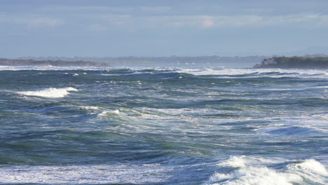 Cámara-Lenta-4.000-Olas-Del-Océano-Azul-Rompiendo-En-El-Mar-Con-Promontorio-En-El-Horizonte,-Australia