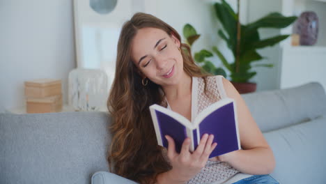 mujer sonriente leyendo un libro en el sofá