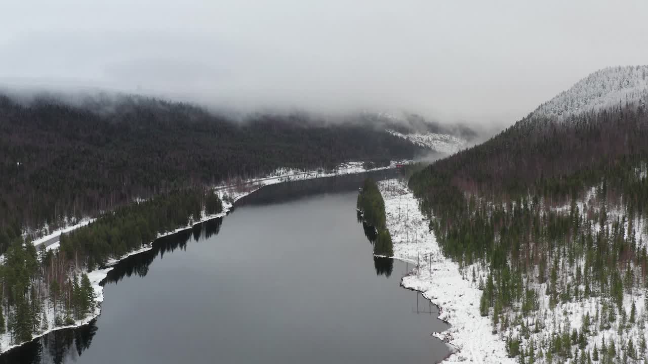 Aerial shot of a partially frozen lake or reservoir in the middle of Sweden during the midwinter solstice. Shot towards the end of the lake.