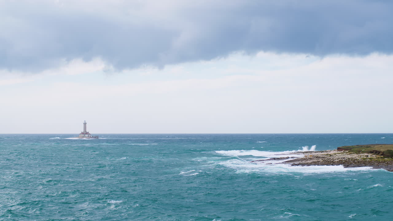 폭풍우 치는 날씨, 불안한 바다, 날아다니는 갈매기의 큰 파도 아래 등대 구멍과 페놀리가 섬