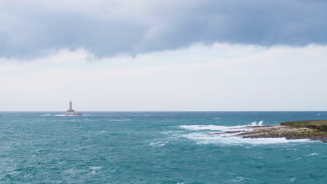 Lighthouse-Porer-and-Fenoliga-island-under-big-waves-on-stormy-weather,-restless-sea,-seagulls-flying