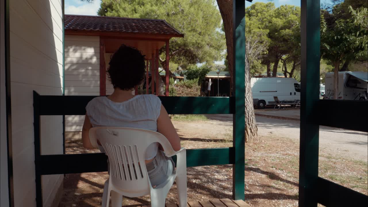 Mujer sentada en una silla de patio en un parque de vacaciones.