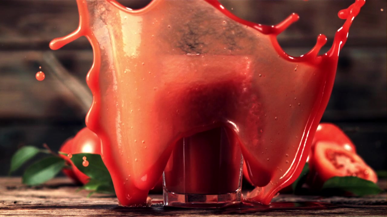 Succo di pomodoro fresco che schizza in un bicchiere con pomodori