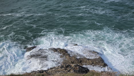Looking-down-a-cliff-face-at-the-waves-crashing-on-the-rocks-below