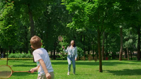 Joyful-mother-play-badminton-with-son-in-park.-Happy-family-have-fun-outdoor.