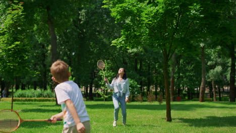 joyful mother play badminton with son in park. happy family have fun outdoor.