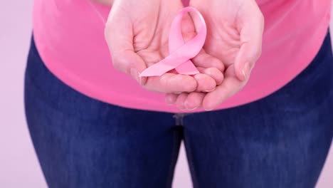 Video-of-midsection-of-caucasian-woman-holding-pink-cancer-awareness-ribbon