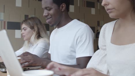 diverse group of coworkers sitting at counter, working with laptops