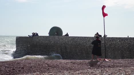 person walking on beach with red flag