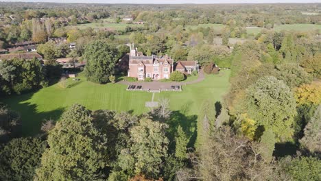 aerial view of a large tudor-style mansion in a park-like setting