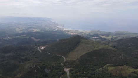 Misty-drone-flight-over-cooling-green-valleys-and-ocean-in-the-distance