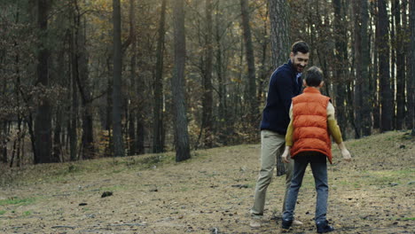 Cheerful-Caucasian-dad-playing-with-a-wooden-plane-and-his-small-son-trying-to-reach-it-and-take-it-from-father-in-the-wood