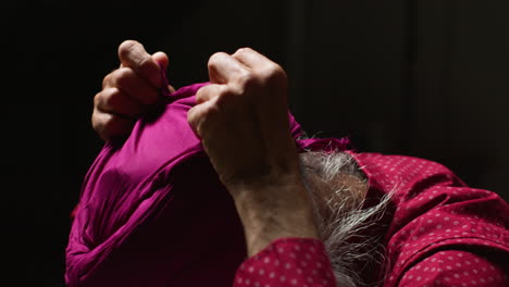 close-up of a man adjusting his pink turban