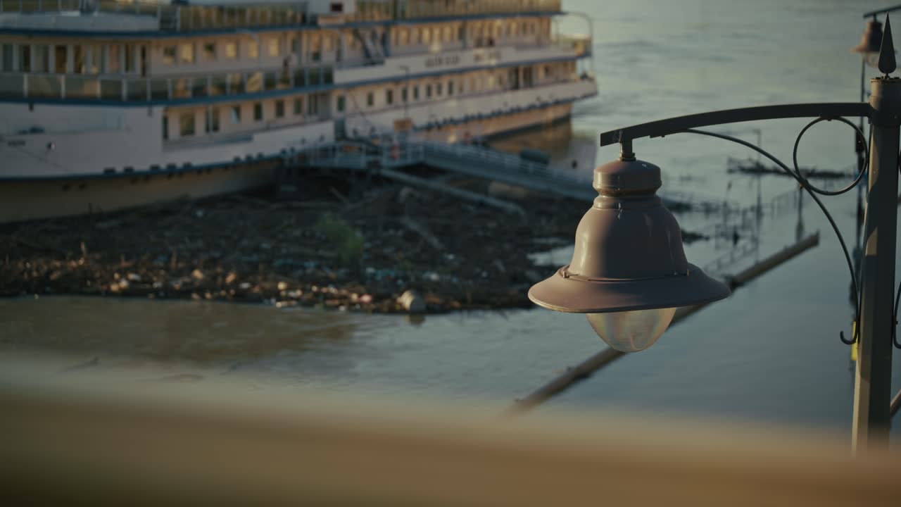 docked boat surrounded by flood debris, with a streetlamp in the foreground during Budapest Flood 2024