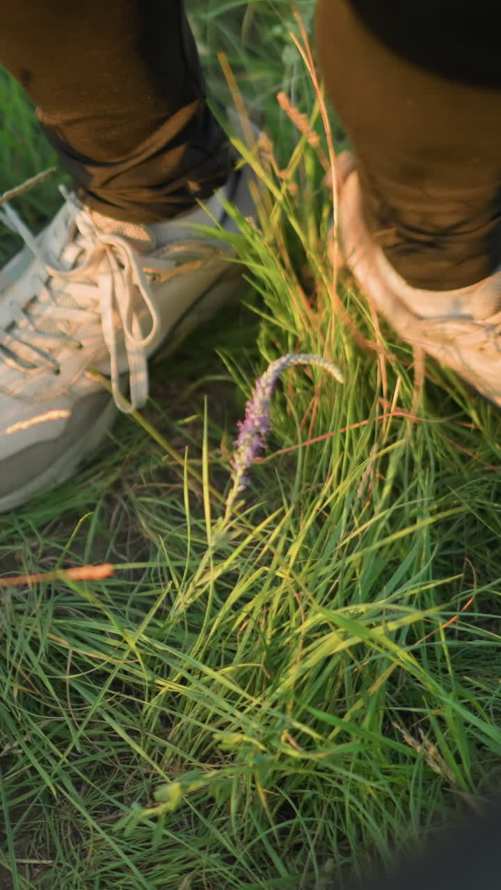 un primer plano de las piernas en pantalones negros y zapatillas blancas, bailando ligeramente en la hierba cerca de un cubo negro