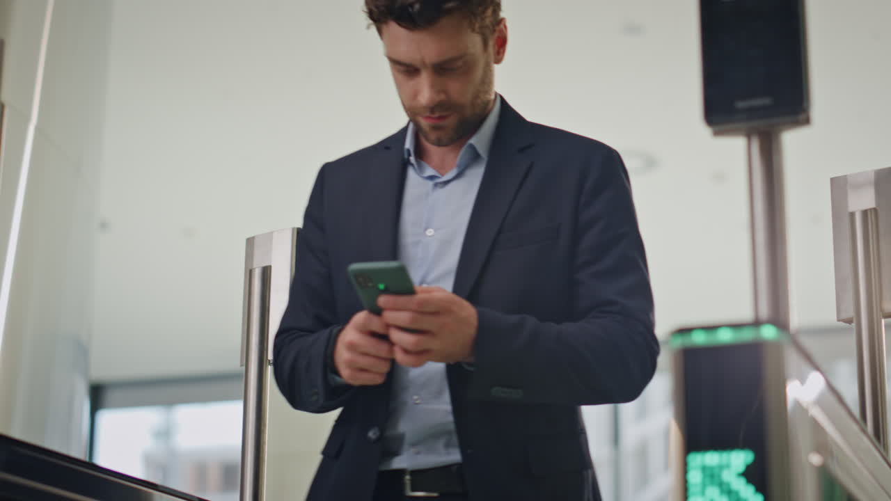 director pasando por la seguridad de la oficina deslizando la tarjeta mirando el teléfono inteligente. gerente ocupado