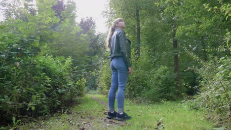la chica se para en el camino de la naturaleza y mira con asombro, ángulo bajo