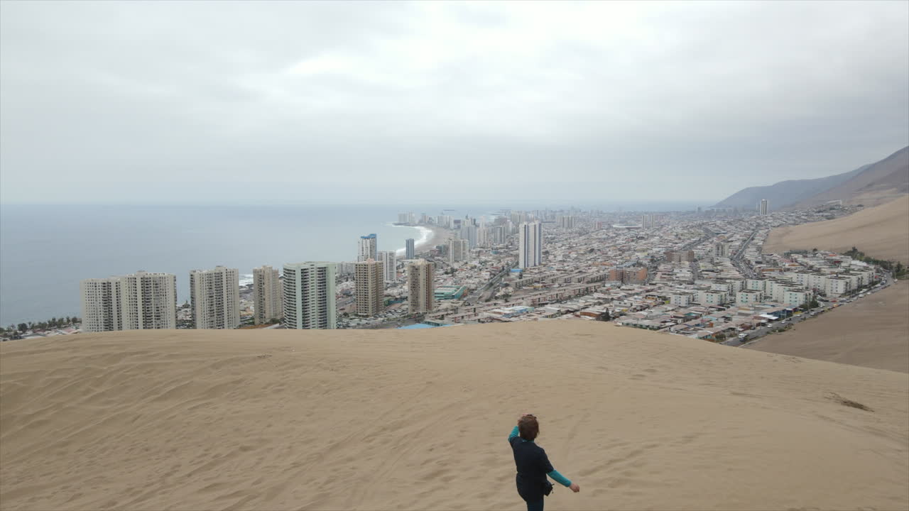 tomada aérea de un turista que toma un video para llegar a la cima de la famosa duna cerra dragon en tarapaca, iquique, chile, américa latina
