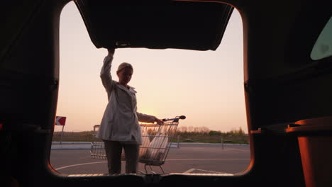 young woman puts shopping carts in the trunk of her car