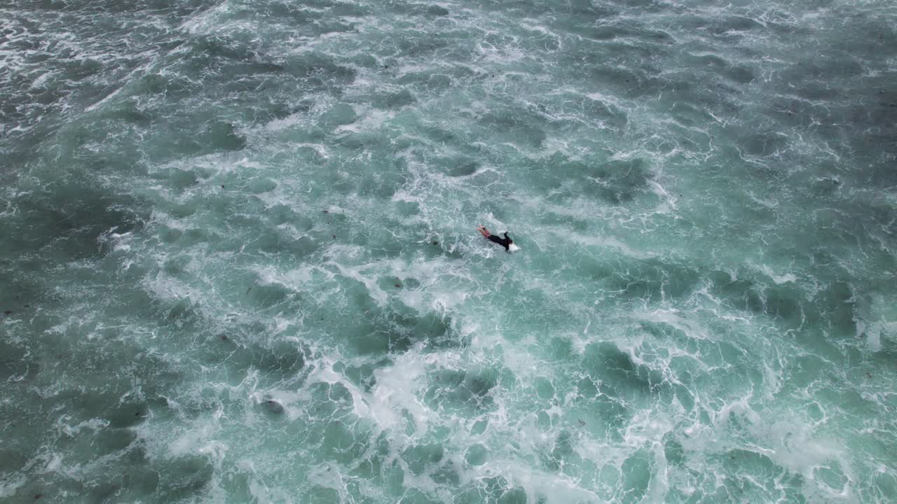 산 비센테 데 라 바르케라의 플라야 메론 해변에서 큰 파도 위를 헤엄치는 서퍼들의 공중 드론 샷