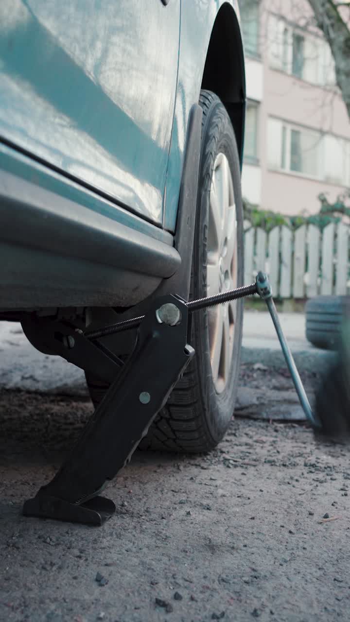 차를 들어올리는 남자. 타이어 교체 과정