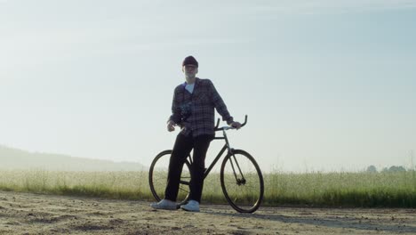 man op een fiets in een veld bij zonsopgang