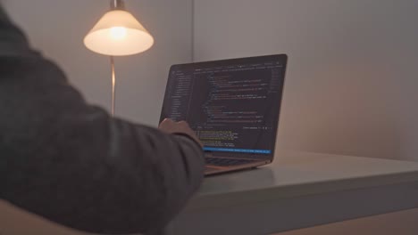 young male hands appear and move toward an open laptop computer where software editing code is on display