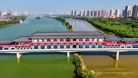 aerial view of a traditional bridge spanning the weihe river, with high-rise buildings in the backdrop, located in the scenic area of xi'an and xianyang in shaanxi province, china.