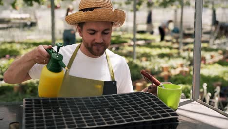 Portrait-of-a-male-gardener-spraying-water-on-a-seedling