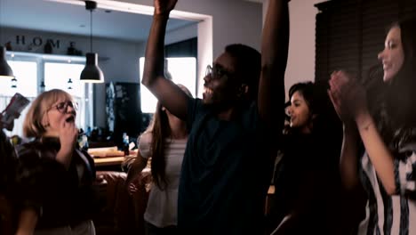 successful african american freelance worker celebrating victory with multiethnic colleagues at house party slow motion