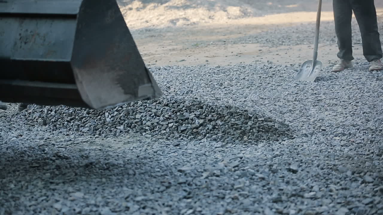 Manual Labor On Construction Site. Construction workers during asphalting road works wearing coveralls