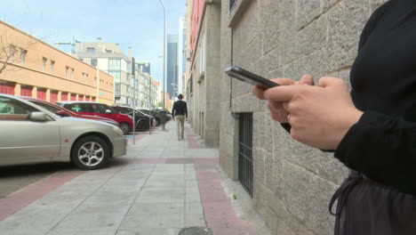person walking and using a smartphone on a city street