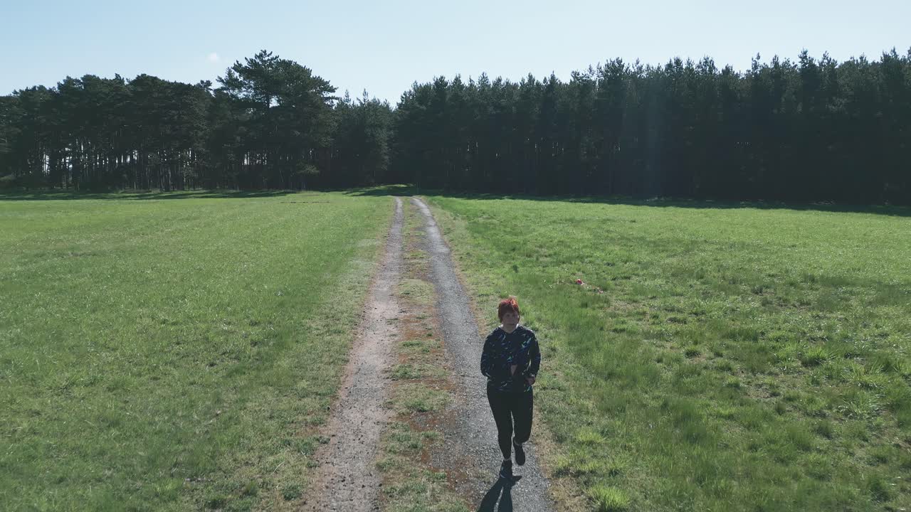 옷을 입고 숲에서 길을 달리는 여자의 넓은