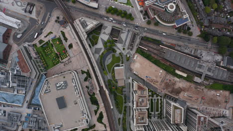 Aerial-birds-eye-overhead-top-down-view-of-modern-city-borough-with-transport-infrastructure.-Tall-residential-buildings-next-to-train-station.-London,-UK