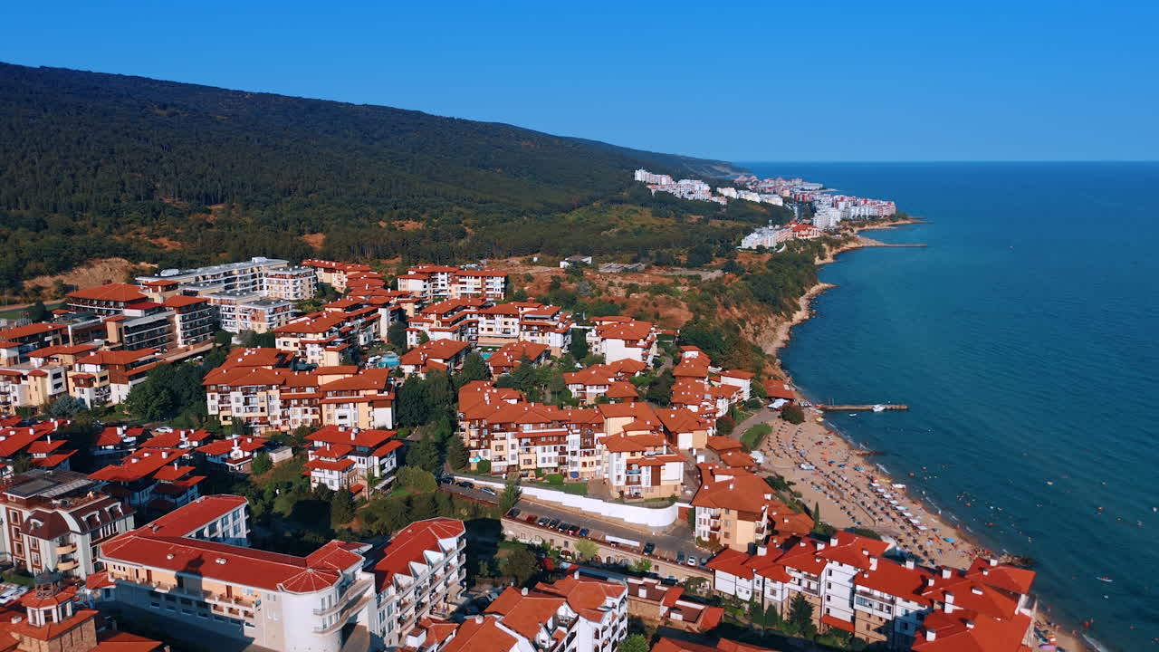 Coastal town with beautiful red rooftops. Vibrant coastal town features charming architecture and beaches under clear blue skies during summer