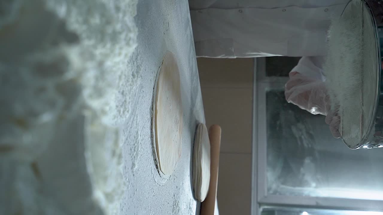 Turecki cukiernik przesiewający mąkę na ciasto baklava, wideo w zwolnionym tempie, pionowe.