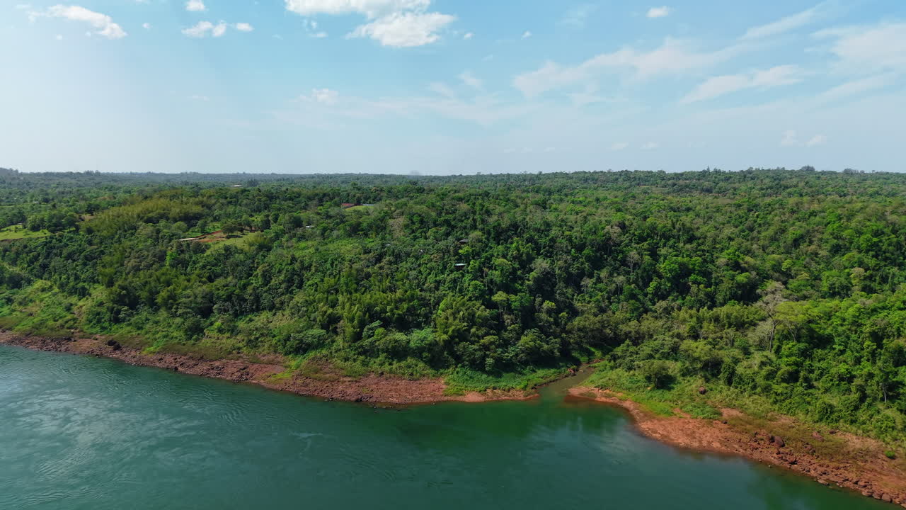 Low daisy cutter forward glide over sunlit Paraná River and the dense Atlantic Forest canopy during sunny afternoon