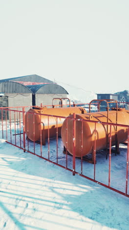 large metal storage tanks on a snowy industrial site