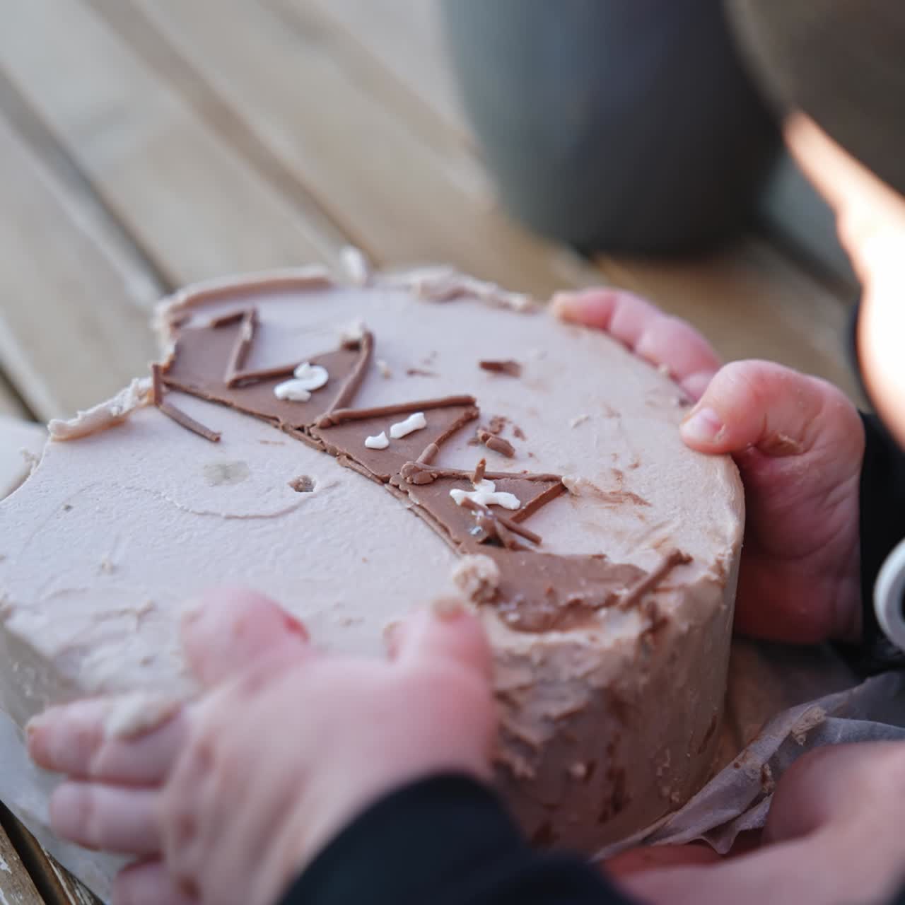 Neonato sconosciuto che cerca di afferrare una torta davanti a sé. Neonata con il ciuccio che prende la crema dal dolce. Primo piano