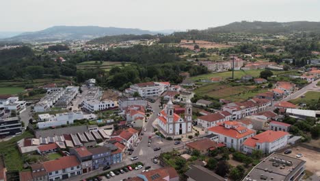 aerial - white baroque church with twin towers in a rural portuguese village on sunny day