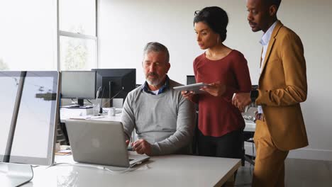 Executives-discussing-over-laptop-at-desk-4k