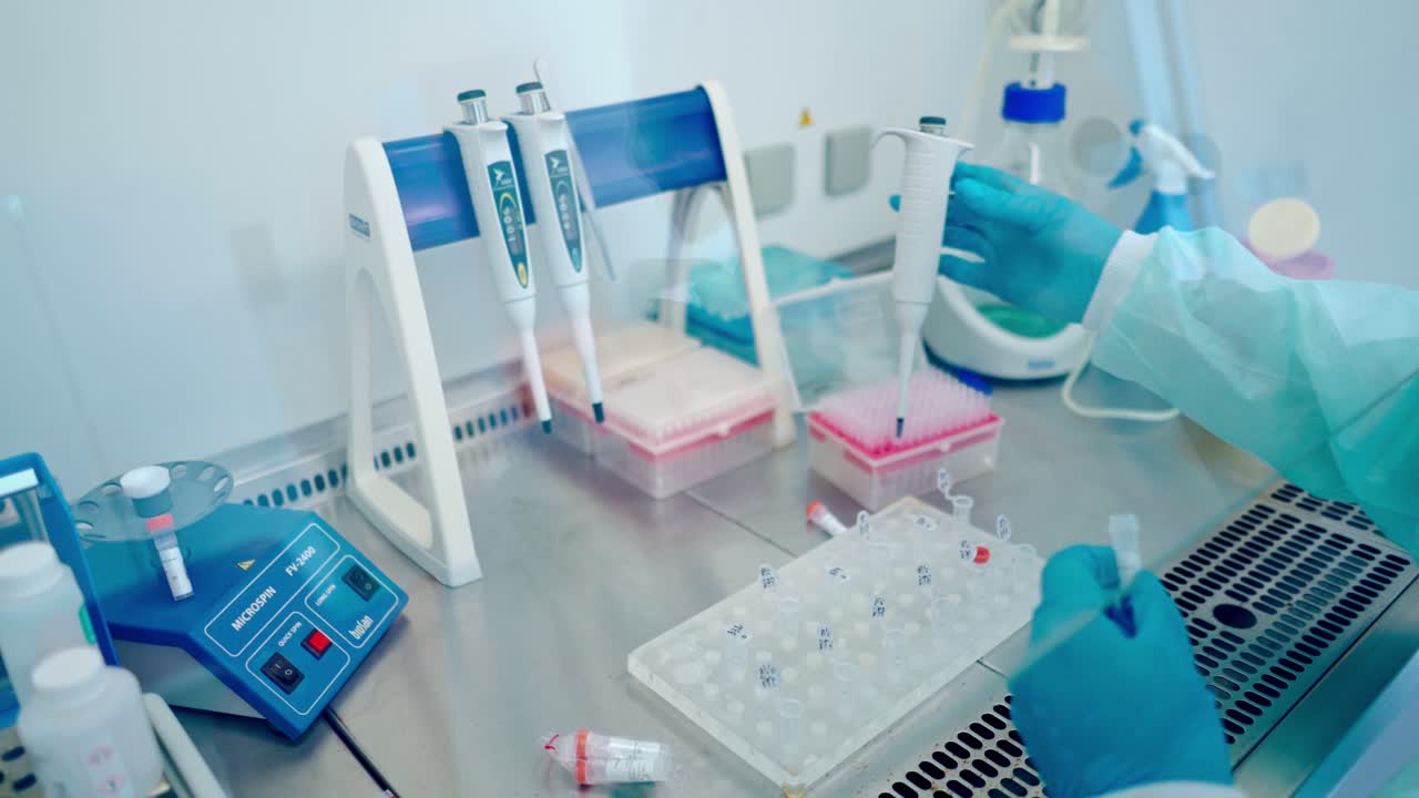 Laboratory worker with test tubes. Modern laboratory indoors. Medical assistant in sterile gloves filling vial with liquid in research lab.