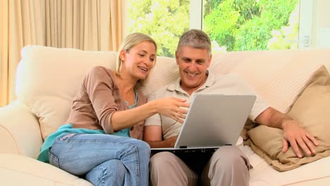 pareja feliz relajándose con una computadora portátil