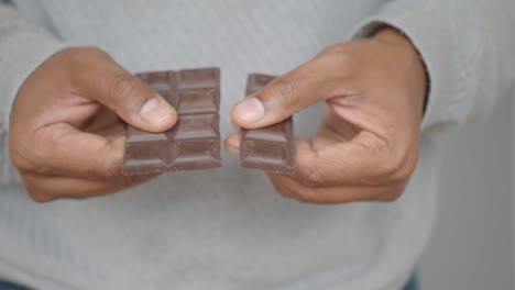 persona que sostiene una barra de chocolate oscuro